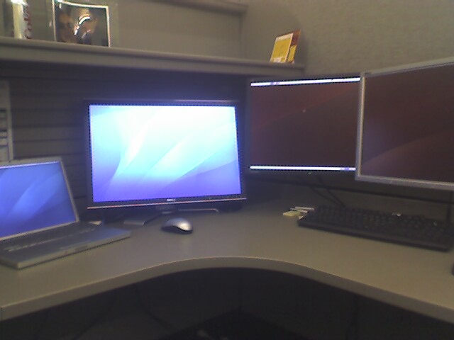 Computer desk with laptop and three monitors